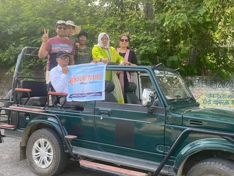 Suri Tours clients on an open safari jeep holding the Suri Tours banner